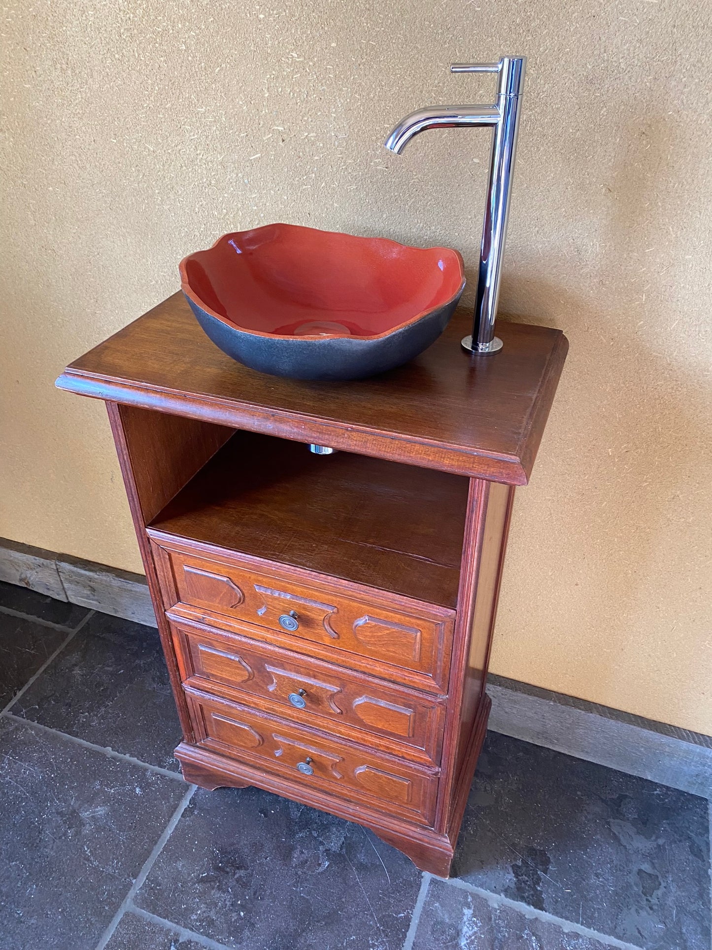 Vintage sanitair meubeltje met rode keramische spoelbak en een elegant kraantje