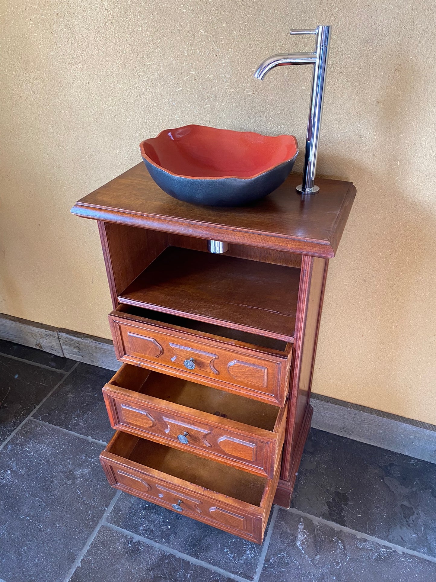 Vintage sanitair meubeltje met rode keramische spoelbak en een elegant kraantje