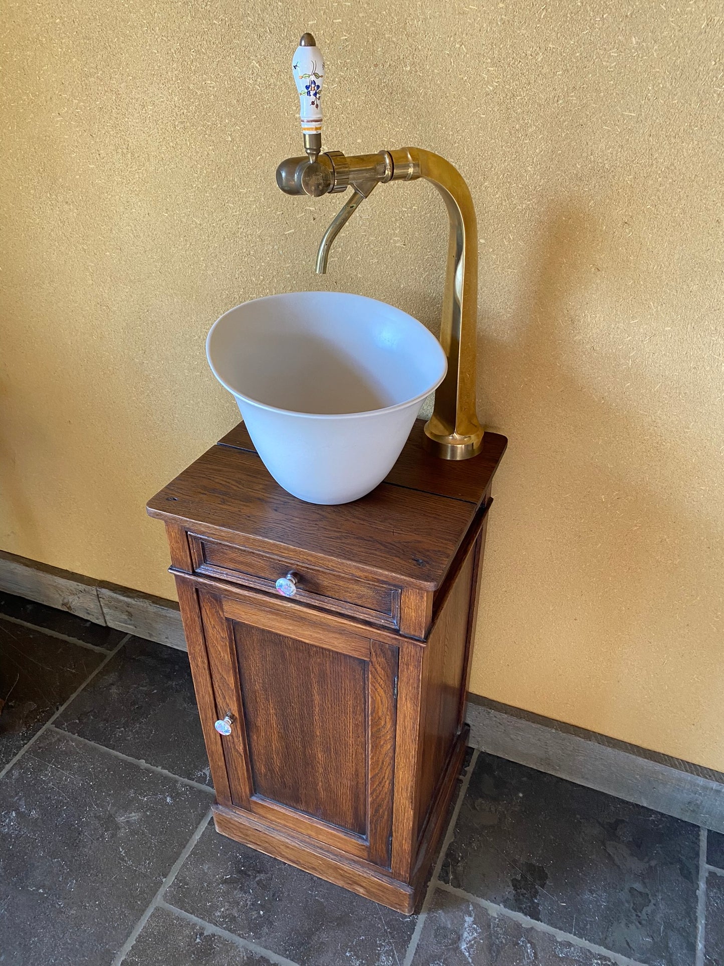 Vintage sanitair meubeltje met witte keramische spoelbak en een originele tapkraan